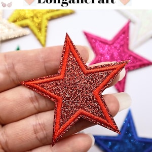 May include: A red glitter star patch with a red embroidered outline. The star is held in a hand, with other star patches in yellow, pink, and blue visible in the background. The text "Longancraft" is at the top.