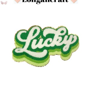 May include: Green and white felt patch with the word "Lucky" in a retro font with a gold outline.