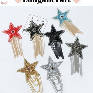 Peut inclure: Assortiment de six patchs thermocollants en forme d'étoile avec des chaînes pendantes. Les étoiles sont ornées de strass de différentes couleurs, dont le rouge, le noir, le bleu, l'argent et l'or.