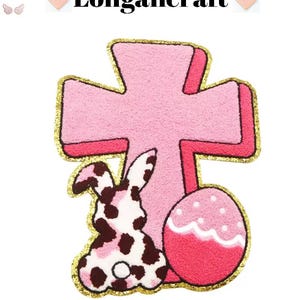 May include: Pink felt Easter cross with a brown and white bunny and a pink Easter egg with white polka dots and a white wavy line.