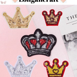May include: Five different crown-shaped iron-on patches. The crowns are made of sequins and have a variety of colours, including gold, silver, red, and black.