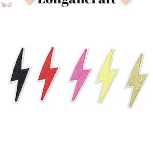 May include: Five embroidered iron-on patches in the shape of a lightning bolt. The patches are black, red, pink, yellow, and gold.