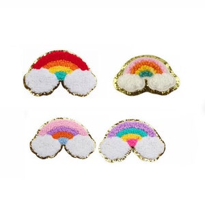 Peut inclure: Quatre patchs arc-en-ciel avec des nuages blancs moelleux. Chaque patch a un schéma de couleurs différent, y compris le rouge, l'orange, le jaune, le vert, le bleu, le violet et le rose.