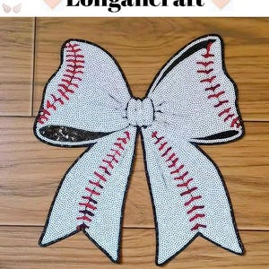 Pode incluir: Um laço branco de lantejoulas com costuras vermelhas, que se assemelha a uma bola de beisebol, é um remendo decorativo para roupas ou artesanato.