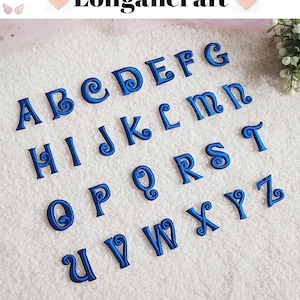 Può includere: Un set di 26 lettere dell'alfabeto ricamate in blu con un design a spirale decorativo. Le lettere sono disposte in ordine alfabetico su una superficie bianca e soffice.