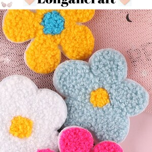 May include: Four fuzzy flower-shaped fabric patches in yellow, blue, white, and pink. The patches are on a pink mesh background.
