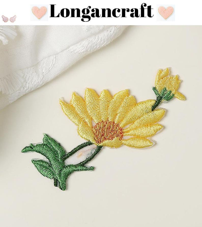 May include: Embroidered yellow daisy patch with green leaves and stem. The patch has a detailed design with a textured appearance. The text "Longancraft" is displayed at the top of the image.