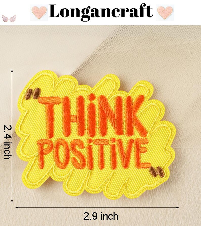 Pode incluir: Etiqueta de ferro bordada amarela com o texto "Think Positive" em letras laranja. A etiqueta mede 7,4 cm de largura e 6,1 cm de altura.
