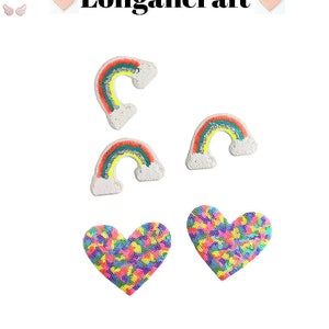 May include: Four iron-on patches, two rainbow-colored and two heart-shaped. The rainbow patches are white with a multi-colored rainbow design. The heart patches are multi-colored with a sequin design.