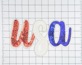 May include: USA spelled out in red, white and blue sequins. The letters are in a cursive font and are on a white grid background.