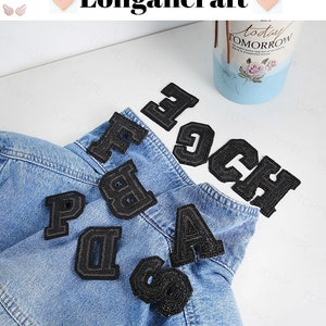 May include: Black felt letter patches in various sizes, including the letters A, B, C, D, F, G, H, and P. The patches are arranged on a blue denim jacket.