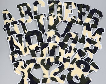 May include: A set of iron-on patches featuring the alphabet in a camouflage pattern. The patches are made of a soft, fuzzy material and are perfect for adding a touch of personality to clothing, bags, or other accessories.