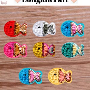 May include: A collection of seven colorful fish-shaped embroidered patches. Each patch features a two-toned design with a sequined tail. The patches are in various colors, including red, white, blue, pink, yellow, and green. The text "Longancraft" is at the top.