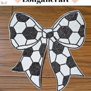 Può includere: Un fiocco di tessuto con motivo di pallone da calcio bianco e nero. Il fiocco è fatto di paillettes ed è un abbellimento decorativo.