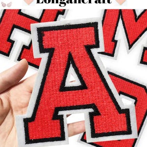 Pode incluir: Patches de letras de feltro vermelho com contornos pretos. As letras são A, M e H. Os patches estão sobre um fundo branco.