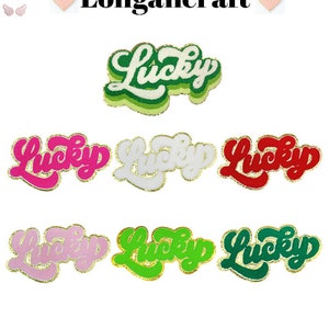 May include: Set of eight iron-on patches featuring the word "Lucky" in a retro, groovy font. The patches are available in a variety of colors, including pink, white, red, green, and light green. Each patch has a gold glitter outline.