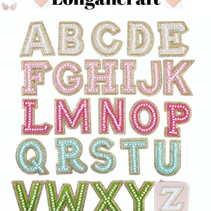 Może przedstawiać: Zestaw 26 liter alfabetu wykonanych z tkaniny i ozdobionych perełkami. Litery są w różnych kolorach, w tym różowym, zielonym, niebieskim i białym. Litery są ułożone w kolejności alfabetycznej.