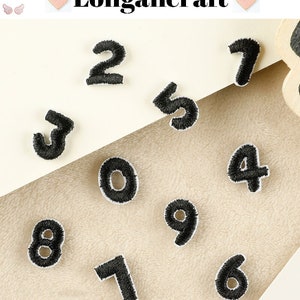 May include: Ten black felt iron-on patches with numbers 0 through 9. The patches are on a beige fabric background.