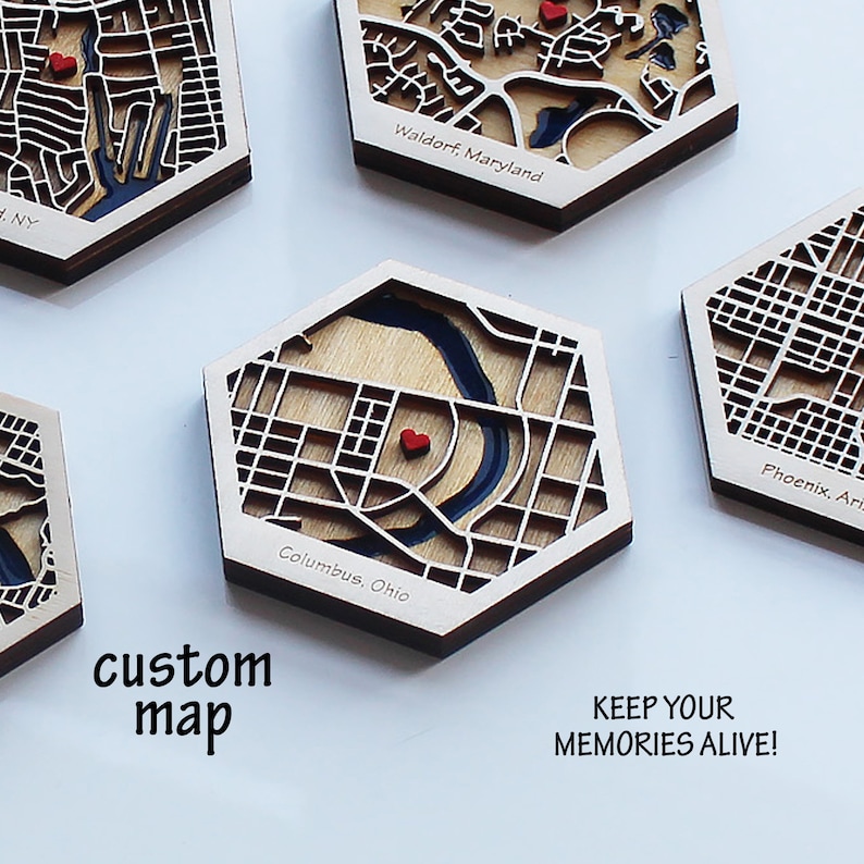 Peut inclure: Sous-verres hexagonaux en bois avec des cartes de ville d&eacute;coup&eacute;es au laser et un c&oelig;ur rouge marquant un emplacement sp&eacute;cifique. Les sous-verres pr&eacute;sentent le texte "Columbus, Ohio", "Waldorf, Maryland" et "Phoenix, Arizona". Le texte "carte personnalis&eacute;e" et "GARDEZ VOS SOUVENIRS VIVANTS !" est &eacute;galement visible.