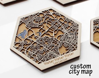 May include: Hexagonal wooden coasters with laser-cut city map designs. The coasters feature intricate street patterns, with text that reads "Water Water Water Loo Loo Loo" and "custom city map". Some coasters have text that reads "Adampur" and "Brampton Home".