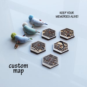 Peut inclure: Cinq sous-verres hexagonaux en bois avec un design de carte personnalis&eacute;e. Chaque sous-verre pr&eacute;sente une carte d&eacute;taill&eacute;e d'une ville avec un point rouge marquant un emplacement sp&eacute;cifique. Le texte "KEEP YOUR MEMORIES ALIVE!" est imprim&eacute; en noir en haut de l'image. Le texte "custom map" est imprim&eacute; en noir en bas de l'image.