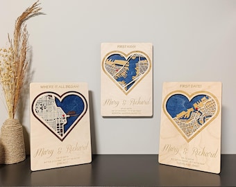 May include: Three wooden heart-shaped plaques with city map designs. Each plaque features a different city map, with the names "Mary & Richard" and dates. The plaques are displayed on a dark surface against a light gray wall.