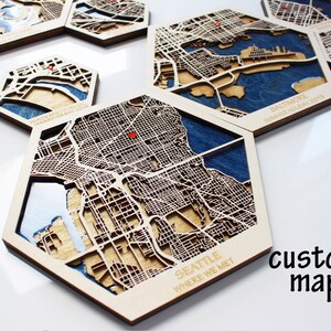 Peut inclure: Carte hexagonale en bois de Seattle, Washington avec le texte "Seattle Where We Met" en bas. La carte est d&eacute;coup&eacute;e au laser et pr&eacute;sente une palette de couleurs bleue et brune. Le mot "carte personnalis&eacute;e" est &eacute;crit en noir sur fond blanc.