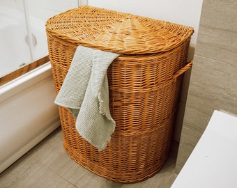 May include: A woven wicker laundry basket with a light green towel hanging over the edge. The basket is in a bathroom setting.