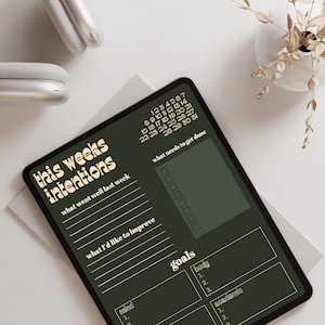 Op de afbeelding: Een digitale planner op een tablet met een donkergroene achtergrond en crèmekleurige tekst. De planner heeft de titel "Deze week's intenties" en bevat secties voor "Wat ging er vorige week goed", "Wat ik wil verbeteren", "Wat moet worden gedaan" en "Doelen". De doelsectie is onderverdeeld in vier categorieën: "Geest", "Lichaam", "Werk" en "Academisch".