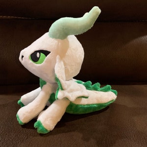 Puede incluir: Un drag&oacute;n de peluche blanco con detalles verdes. El drag&oacute;n tiene un gran cuerno verde y alas verdes. Tiene grandes ojos verdes y un cuerpo blanco.