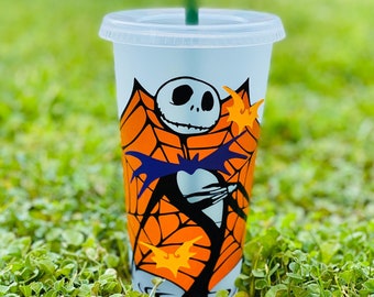 May include: A white reusable cup with a black and orange design featuring Jack Skellington from The Nightmare Before Christmas. The design includes a spiderweb and bats.