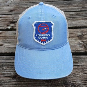 Könnte beinhalten: Eine hellblaue Baseballkappe mit einem weißen Netzrücken. Die Vorderseite der Kappe zeigt einen blauen und weißen Patch mit einem Baseball und dem Text "Conference Champs 1980".