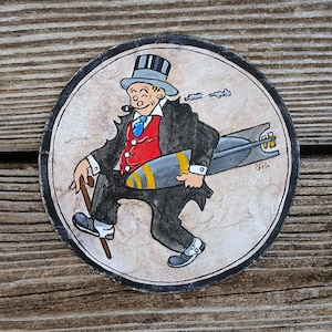 Könnte beinhalten: Handgemaltes, kreisrundes Kunstwerk mit einem Cartoon-Gentleman in Anzug, Zylinder und Gehstock, der eine Bombe trägt. Der Mann raucht eine Pfeife. Das Kunstwerk hat einen schwarzen Rand und ist vor einem hellen Hintergrund platziert.