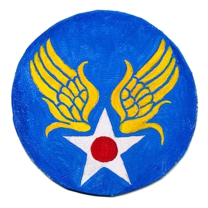 Könnte beinhalten: Ein blauer Lederfleck mit einem weißen Stern und einem roten Kreis in der Mitte. Zwei gelbe Flügel befinden sich auf beiden Seiten des Sterns.