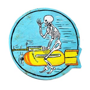Può includere: Grafica rotonda blu chiaro con uno scheletro che cavalca una bomba gialla. Lo scheletro è bianco con dettagli neri, che tiene una sigaretta. La bomba ha accenti arancioni e neri, con un contorno nero.