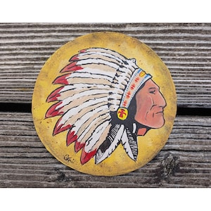 Könnte beinhalten: Runde, handbemalte Kunst mit einem indianischen Häuptling im Profil. Das Kunstwerk zeigt einen Kopfschmuck mit roten und weißen Federn, einen gelben Hintergrund und ein detailliertes Gesichtsprofil. Das Stück ist in der unteren linken Ecke signiert.