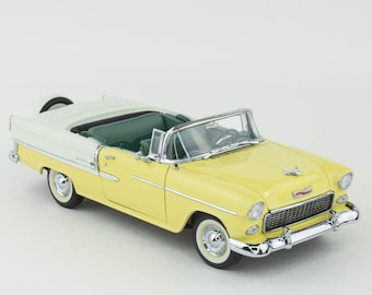May include: A yellow and white 1955 Chevrolet Bel Air convertible model car. The car has a green interior and chrome accents.