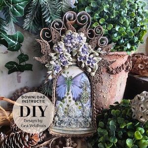 Op de afbeelding: Een handgemaakt DIY-project met een stolp ontwerp met een vlinder illustratie, gemaakt van karton en papieren bloemen. Het kunstwerk bevat decoratieve elementen en de tekst "DOWNLOAD INSTRUCTIE DIY Design by Gea Veldhuis".