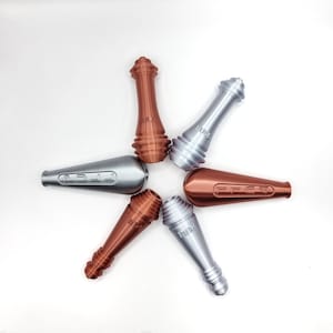 May include: Six silver and copper coloured metal pull tabs with the word "PULL" printed on them. The tabs are arranged in a star shape.