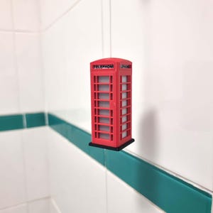 May include: A miniature replica of a classic red telephone box with the word "TELEPHONE" printed on the side.