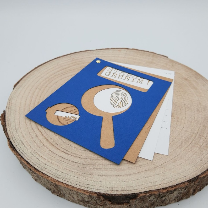 May include: A blue card with a magnifying glass and fingerprint design. The card says "Strictly Secret!" in white text.