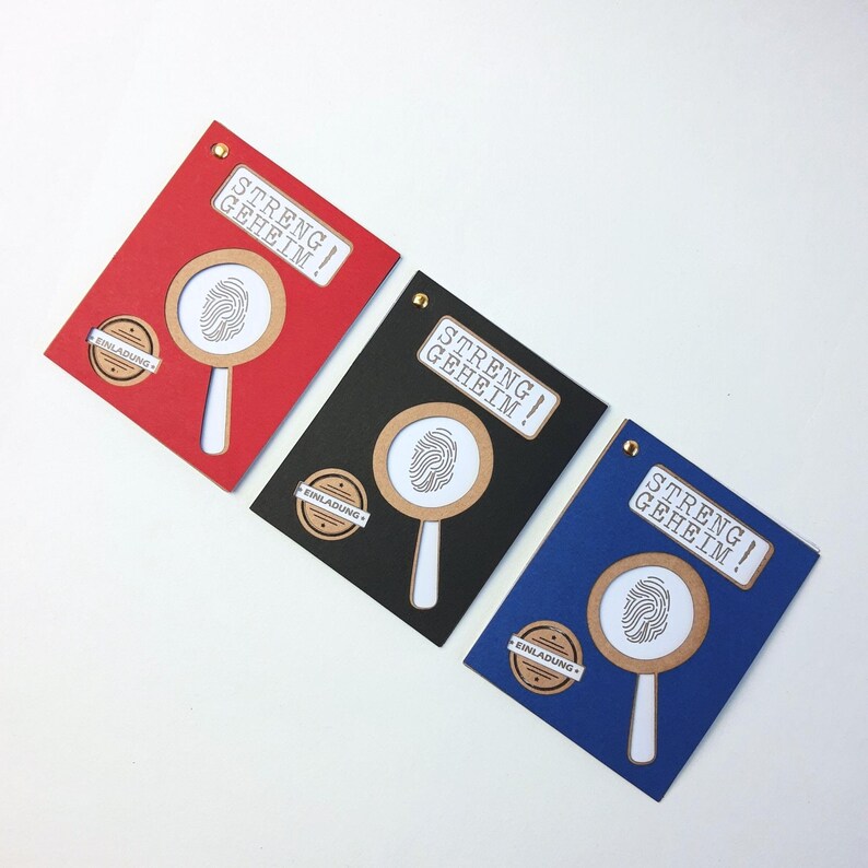 May include: Three invitations with a magnifying glass and fingerprint design. The invitations are red, black, and blue. The text on the invitations reads "Streng Geheim!" which translates to "Strictly Secret!" in English.