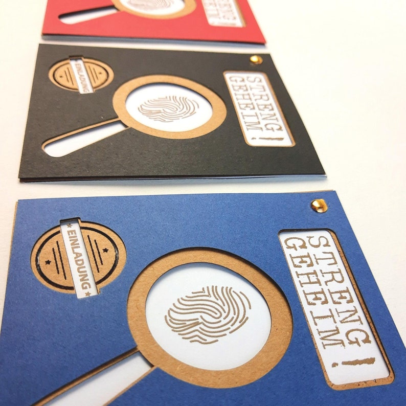 May include: Three invitations with a magnifying glass design. The invitations are blue, black, and red. The text on the invitations reads "streng geheim!" which means "strictly confidential!" in German.