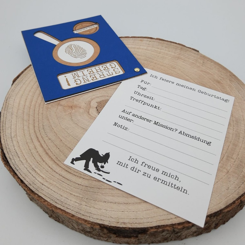 May include: A blue and brown card with a fingerprint cutout and the text "Streng geheim" (German for "Strictly confidential"). The card has a section for writing down details for a birthday party, including the date, time, and location. The card also includes a section for a note and a section for an optional mission.
