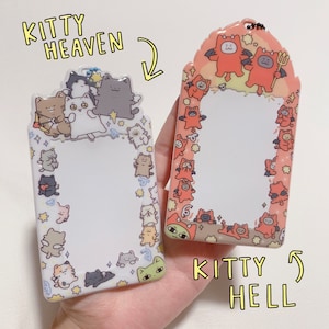 May include: Two clear acrylic cat-themed ID badge holders. One features a border of cartoon cats and the text "Kitty Heaven." The other has a border of devil cats and the text "Kitty Hell."