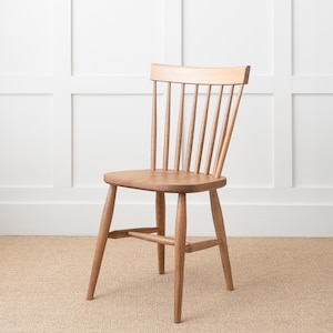 May include: A wooden chair with a slatted back and a simple design. The chair is made of light brown wood and has a natural finish.
