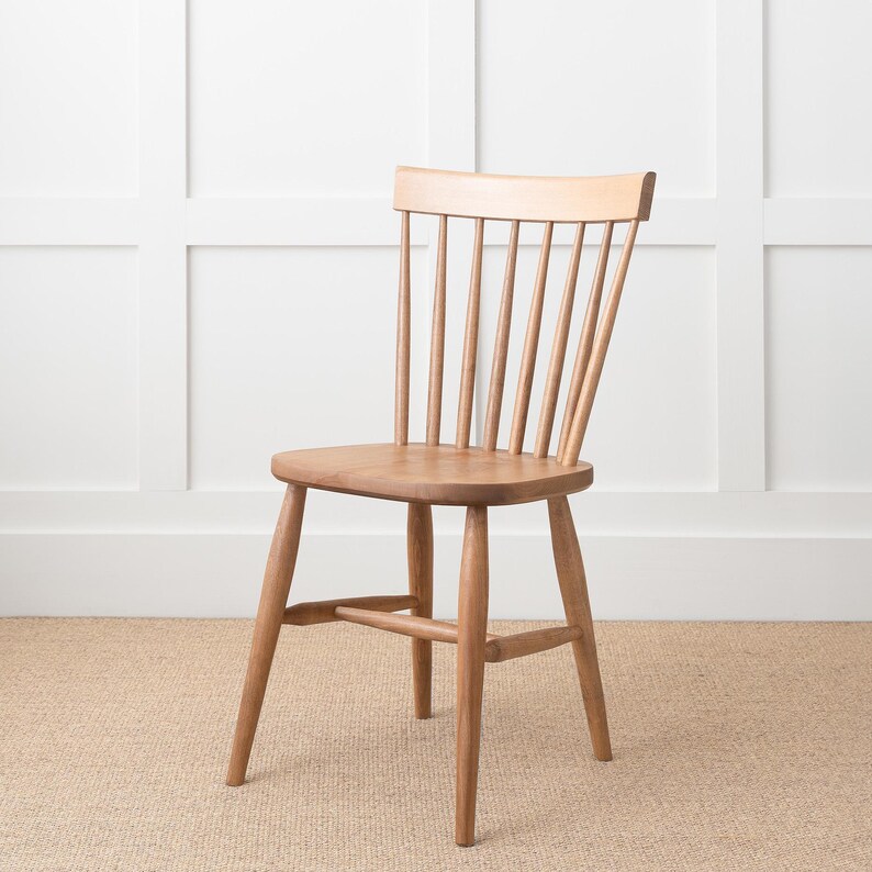 May include: A wooden chair with a slatted back and a simple design. The chair is made of light brown wood and has a natural finish.