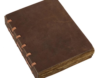 May include: A rectangular, brown leather journal with a worn appearance. The pages are aged, and the spine is hand-stitched with tan-colored thread. The journal is closed, suggesting it is ready for writing or sketching.