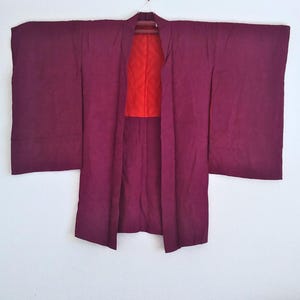 May include: A burgundy kimono with a red lining. The kimono has long sleeves and a wide, open front.
