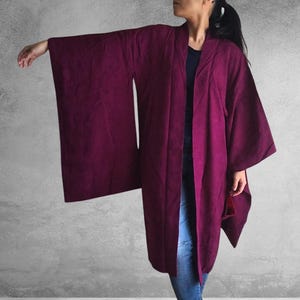 May include: A long, burgundy-colored robe with wide sleeves. The robe is made of a soft, flowing fabric and has a simple, elegant design.